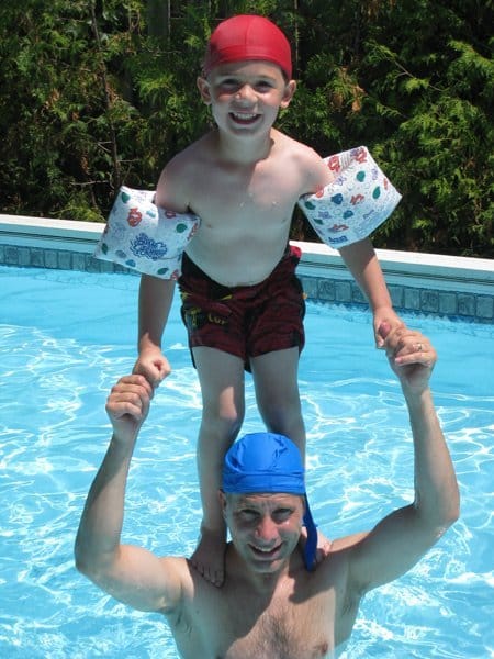 man and child playing in pool with uv protection swim cap