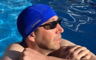 a man in the pool in on vacation wearing nammu classic blue swim cap