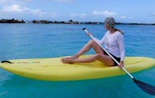woman wearing leopard patter sun protective swim hat on a stand up paddling board