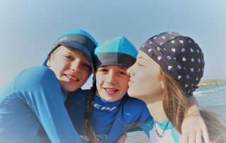 siblings on the beach with variety of nammu sun protective swim hats