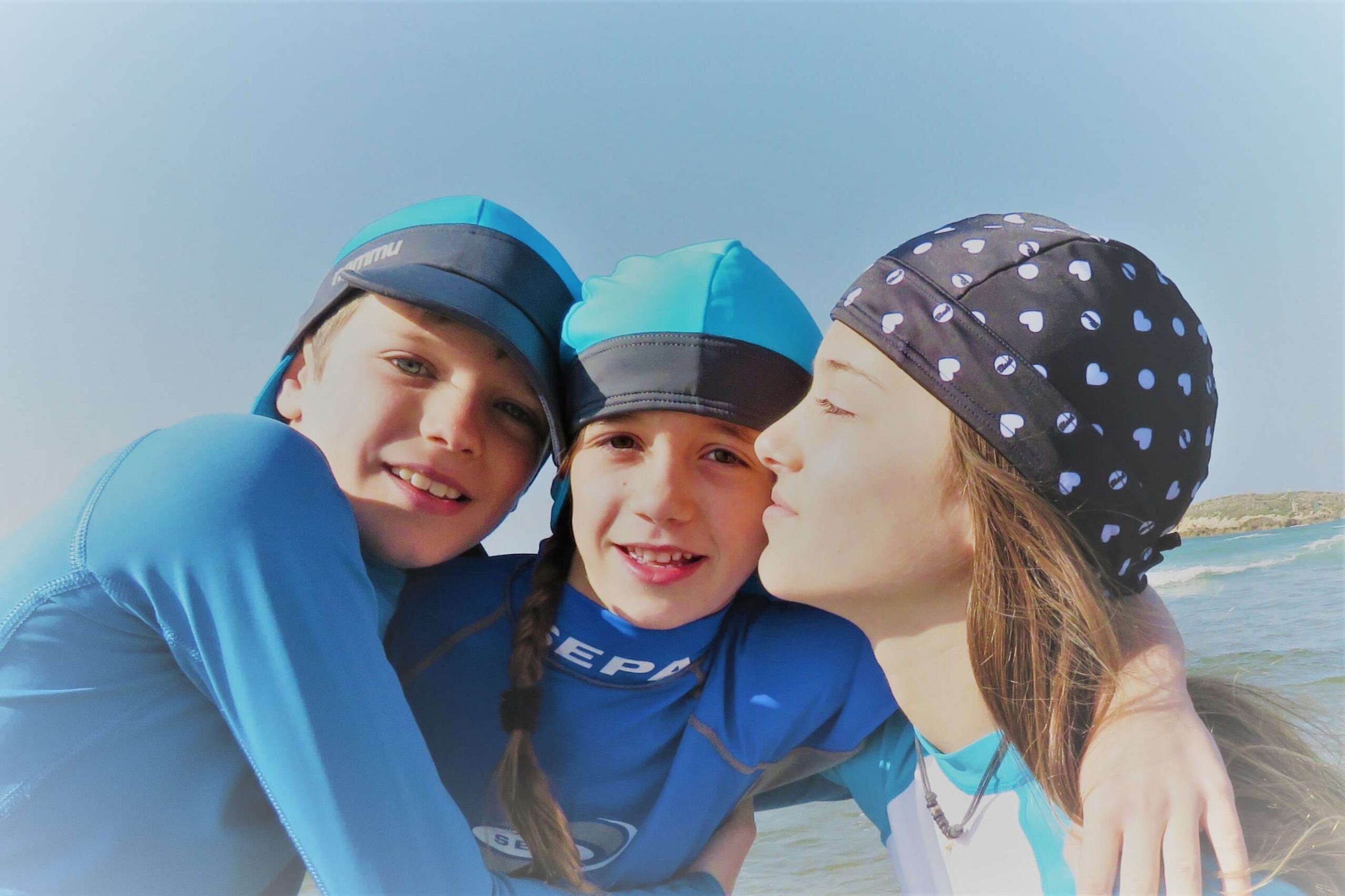 siblings on the beach with variety of nammu sun protective swim hats