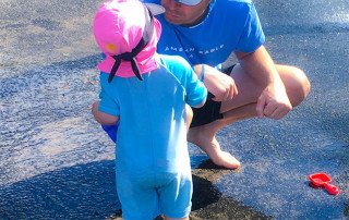 father and daughter wear nammu sun protective swim hats on the splash pads