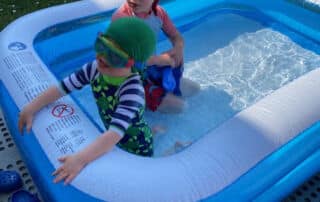 2 brothers boys with sun protective swim caps outdoor pool