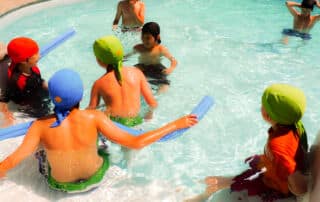 kids in the pool wearing colorful sun protective swim caps