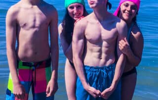 teenagers on the beach wearing colorful sun protective swim caps