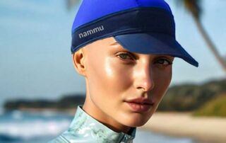 bald woman on the beach swimming with alopecia hat