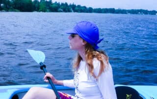 woman in kayak with visor sun protective swim cap