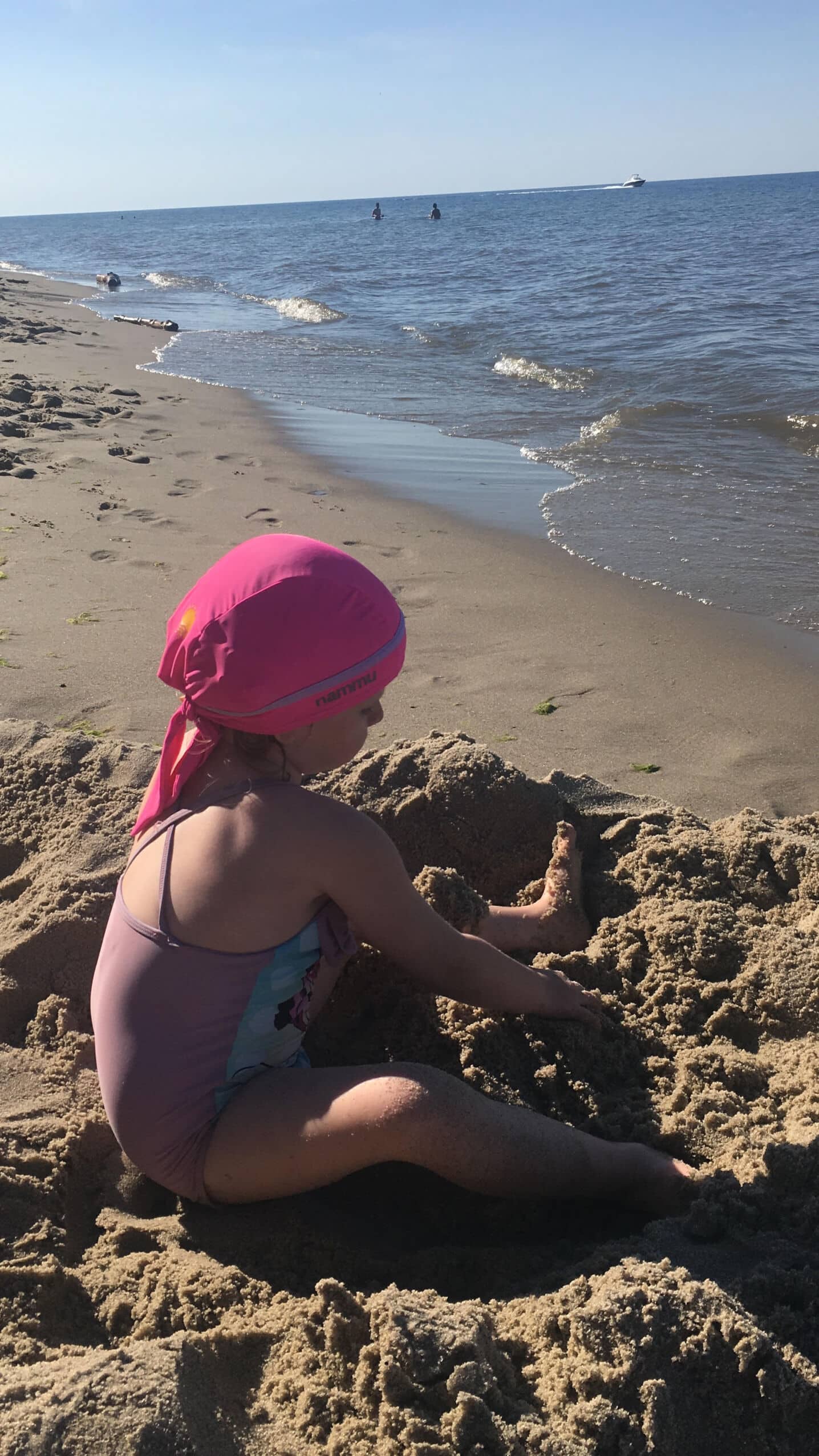 Magdalena girl with cochlear implantes bulding snad castle with pink nammu sun protection swim cap